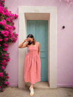 Person in a pink dress standing on a white floor with a gray wall.